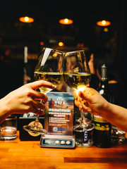 Calm evening in a restaurant, two people making toast and clinking glasses with white wine