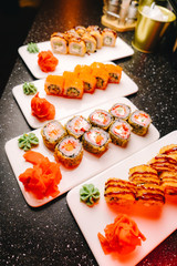 Rich assortment of sushi rolls on white ceramic plates, ready for serving