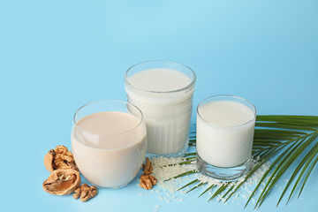 Glasses of different milk on color background