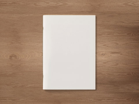 Blank Magazine or Brochure on brown wooden background. Front cover top view. Mockup concept for your showcase.