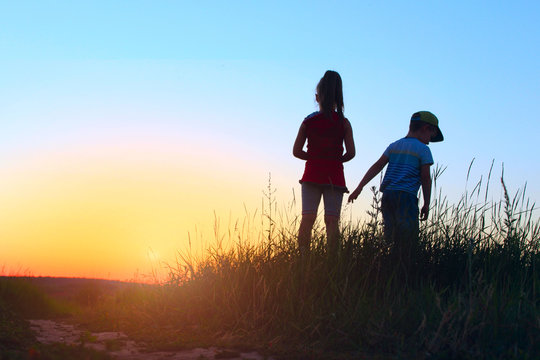 Blurry image of children playing outdoor over blue sky background. Family, childhood, friendship concept.  Kids silhouettes outdoors. Kids silhouettes outside.