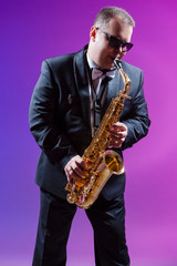 Fototapeta na wymiar Musicians Concepts. Portrait of Expressive Caucasian Saxophonist Against Colorful Background.