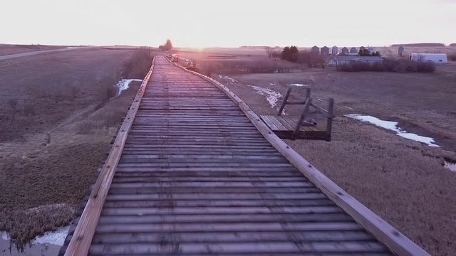 POV aerial: Crossing a rickety, wooden railway trestle at sunrise