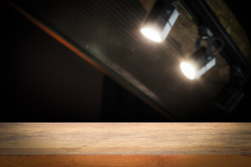 Wooden shelf table floor and wall dark blurred black spotlights, shelf display products.