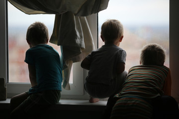 quarantined boys during a coronavirus epidemic sit at home and look out the window