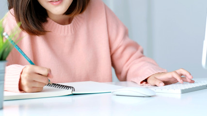 Study online class, Woman hand writing on notebook while tying computer keyboard, Adult female student learning online course, Education and technology, Work from home