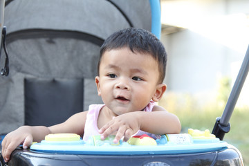 Southeast Asian newborn baby. Sitting on a stroller. Kid is cute.  Infant is 7 months. - People, Health care concept.