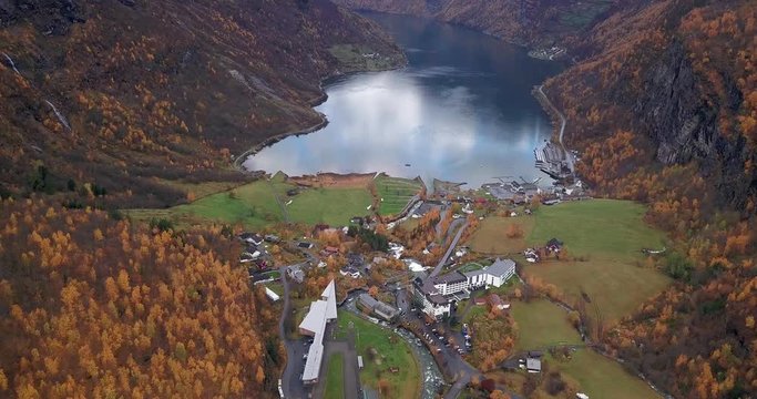 Aerial view of the Geiranger village. The road snaking downhill, hotels and houses occupy the mountainside. Mountain river carrying its' turbulent waters down to the fjord.