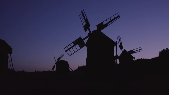 Black windmills silhouette at night. Dark blue sky on background.