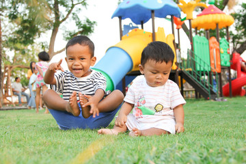 ASEAN boys Fraternal Sitting on the green lawn In the back is a playground