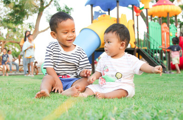 Obraz premium ASEAN boys Fraternal Sitting on the green lawn In the back is a playground