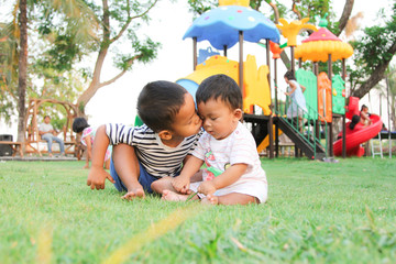 ASEAN boys Fraternal Sitting on the green lawn In the back is a playground