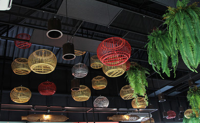 Multicolored bird cages hanging on the roof of a coffee shop.