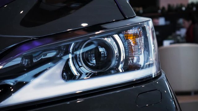 Closeup video left car headlight side span of the camera. Stock. Modern techonology auto details with led and xenon elements inside.