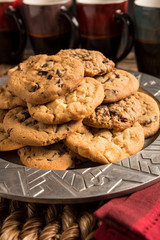 Closeup of a group of assorted flavored cookies. Chocolate chip, macadamia nut, oatmeal raisin, on a silver plate with coffee cups served after dinner or as a snack