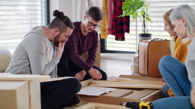 Young people assembling furniture in new home, house sharing concept.
