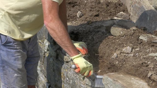 A Male Worker Brushing The Soil On The Concrete Blocks In Devon, UK - closeup shot
