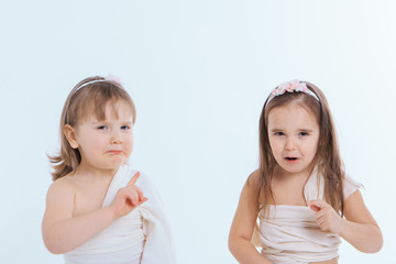 two little girls shake their fingers at a white background. Children raise each other. the concept of education , childhood, and Sisterhood. Copy space