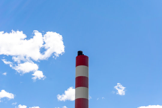 horizontal view of a red and white industrial smokestack chimney under a blue sky