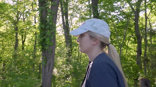 Close tracking shot with a ped up from the side of a young beautiful woman hiking in a dense forest