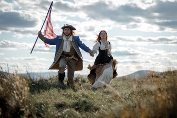 Man in form of officer of War of Independence and girl in historical dress of 18th century. July 4...