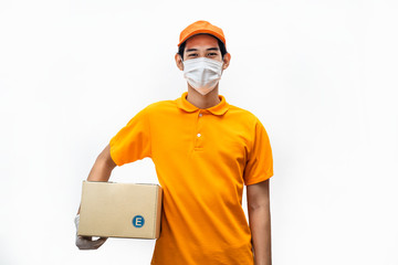 Asian deliver man wearing face mask in orange uniform holding box of food, groceries, things standing in white isolated background. Postman and express grocery delivery service during covid19 pandemic