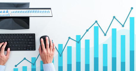Business analysis and calculating. Top view of business man using spreadsheet. Blue graphs and desktop computer.