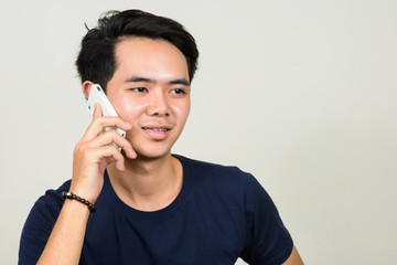 Portrait of happy young Asian man talking on the phone