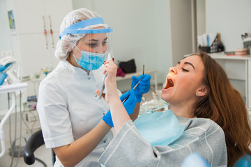 Young female dentist curing patient's teeth filling cavity