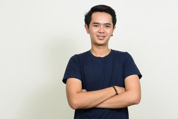 Fototapeta premium Portrait of happy young Asian man smiling with arms crossed