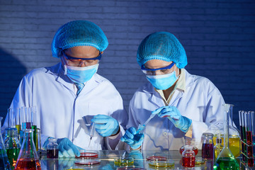 Researchers putting various reagents in petri dishes when working on vaccine in laboratory
