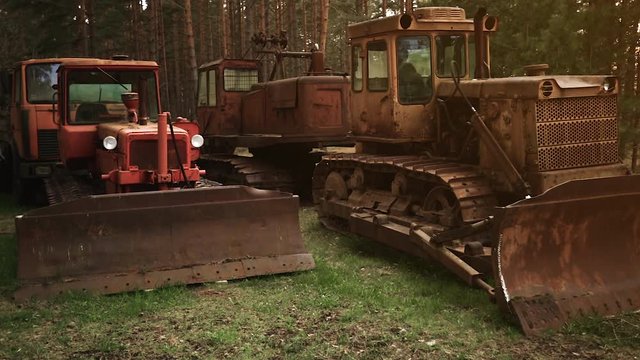 Old rusty abandoned caterpillar tractors with huge loader buckets