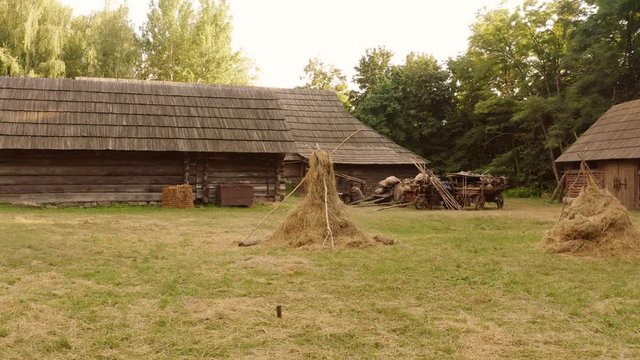 Ancient historical shack cabins. Home for medieval peasants. Yard with hay and rustic wagons.
