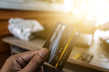 The image of a person holding a blue credit card and deciding to spend online With a blurry...