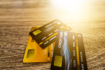All 3 credit cards, with yellow, blue, and black on the light brown wooden table and have flare light in the background. Suitable for use in assembling content.