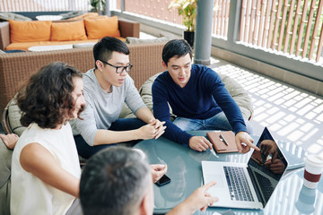 Obraz premium Business team watching presentation on laptop screen and discussing news project and its perspectives