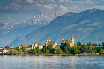View of old city of Rapperswil dominated by its 13th century castle and the alps in the background,...