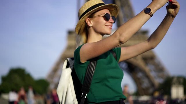 Female tourist enjoying trip in Paris and making photos on modern smartphone walking near Eiffel Tower.Slow motion of young woman travelling and taking picture on mobile phone using 4G internet
