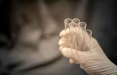 Doctor hand holding test tube and wearing surgical glove preparing to the science experiment in the laboratory room.