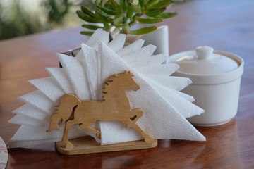 Wooden stand in the form of a horse with napkins, on the background of a succulent
