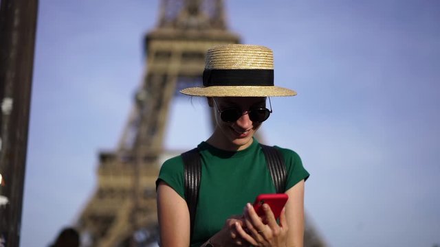Slow motion of happy young woman dialing number on smartphone and calling to friend using roaming connection walking on street of Paris.Hipster girl communicating on mobile phone enjoying trip 
