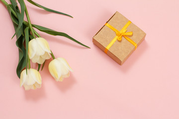 Obraz na płótnie Canvas Gift box with tulip flowers on a pink background.