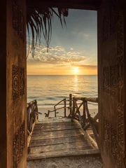Foto op Plexiglas Donkerbruin Mooie dor manier naar wit strand met zonsopgang op de achtergrond. Zanzibar