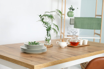 Stack of clean plates and tray with tea on table in dining room