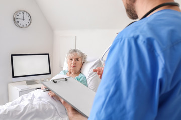 Obraz premium Male doctor working with elderly patient in hospital room