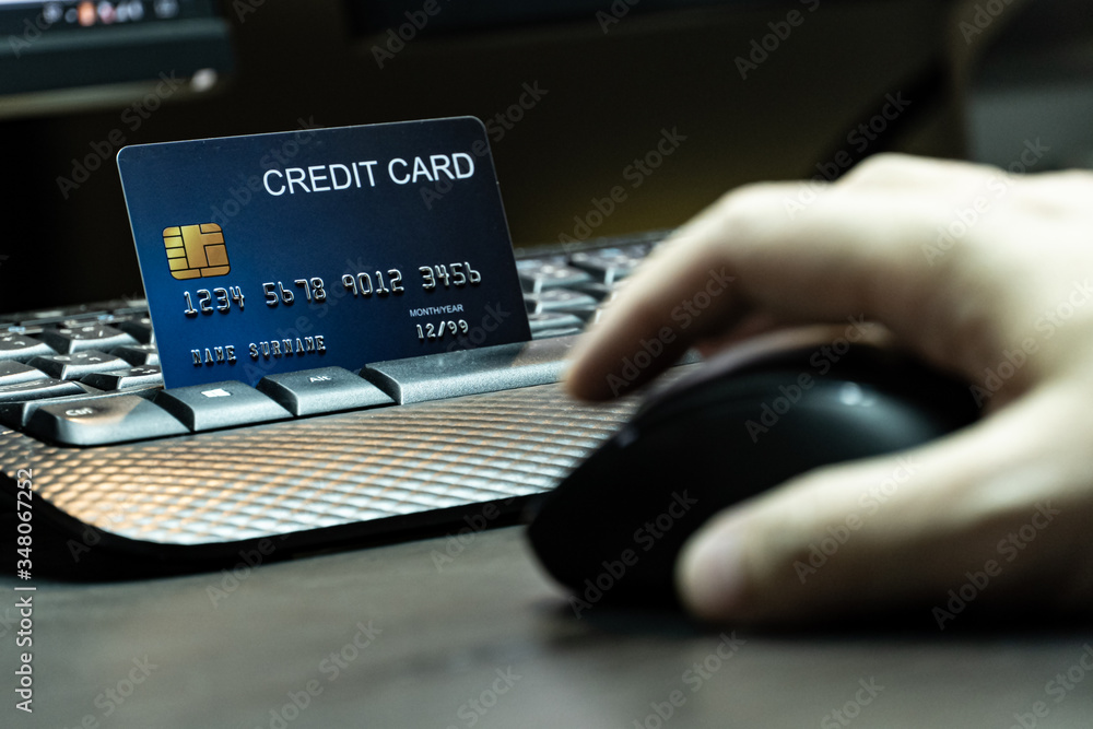Poster close up Shallow focus hand hold mouse with credit card and Computer background. Background for E-commerce and online shopping concept.