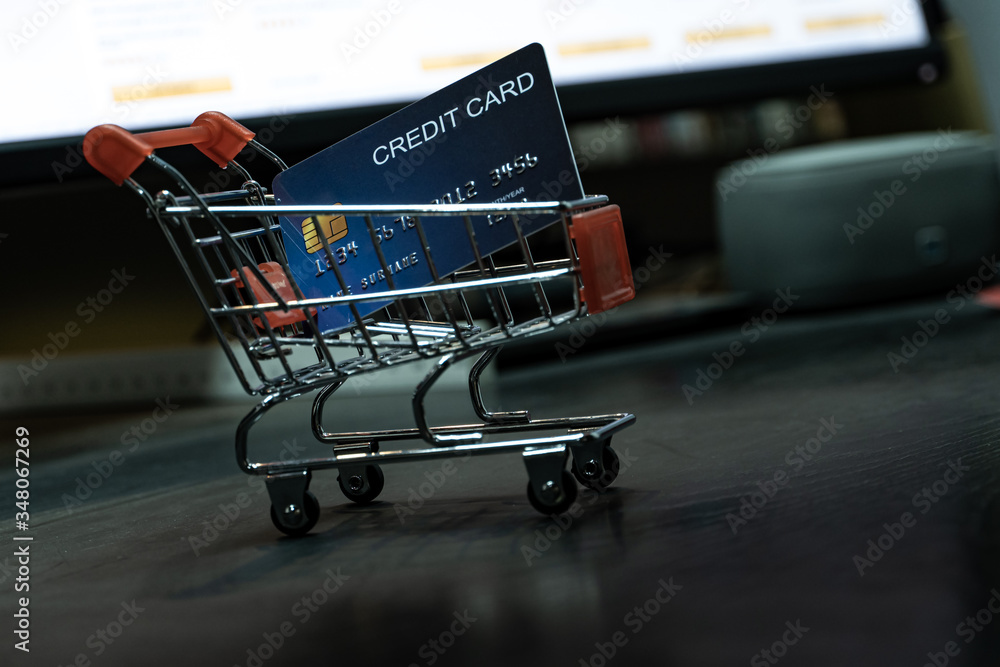Aufkleber close up Shallow focus Credit Card in mini shopping card with Computer keyboard and E-commerce website on monitor background. Background for E-commerce and online shopping concept.