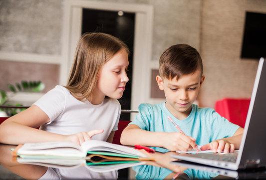 Boy And Girl, Brother And Sister Study At Home. Older Sister Helps Younger Brother Do Homework