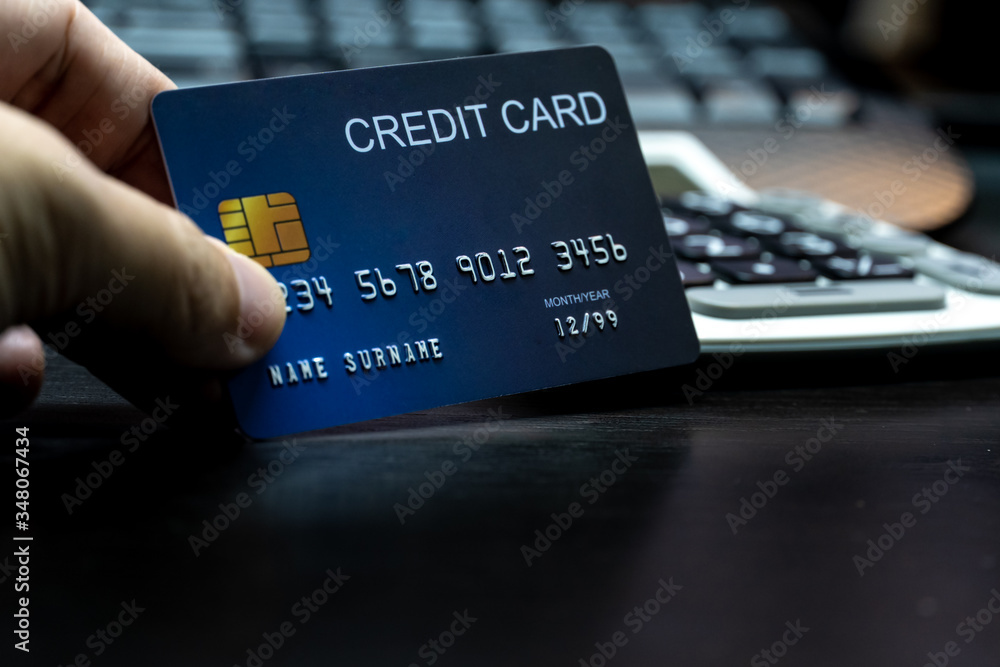 Poster close up Shallow focus hand hold Credit Card on Computer keyboard. Background for E-commerce and online shopping concept.