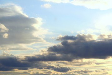 Clouds in the blue sky at sunset or dawn backlit by the sun. Place for text and design.